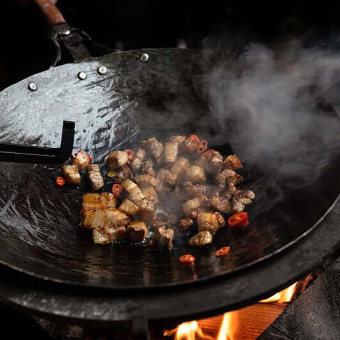 Handgeschmiedete Wok-Pfanne ∅ 40cm mit gebratenem Fleisch und Chili, nachhaltig und qualitativ hochwertig.